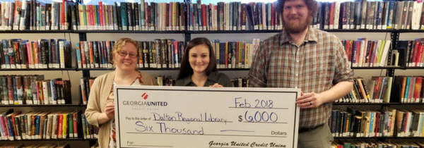 Personal de la biblioteca con miembro de Georgia United Credit Union sosteniendo un cheque gigante para el Math Tutoring Program.