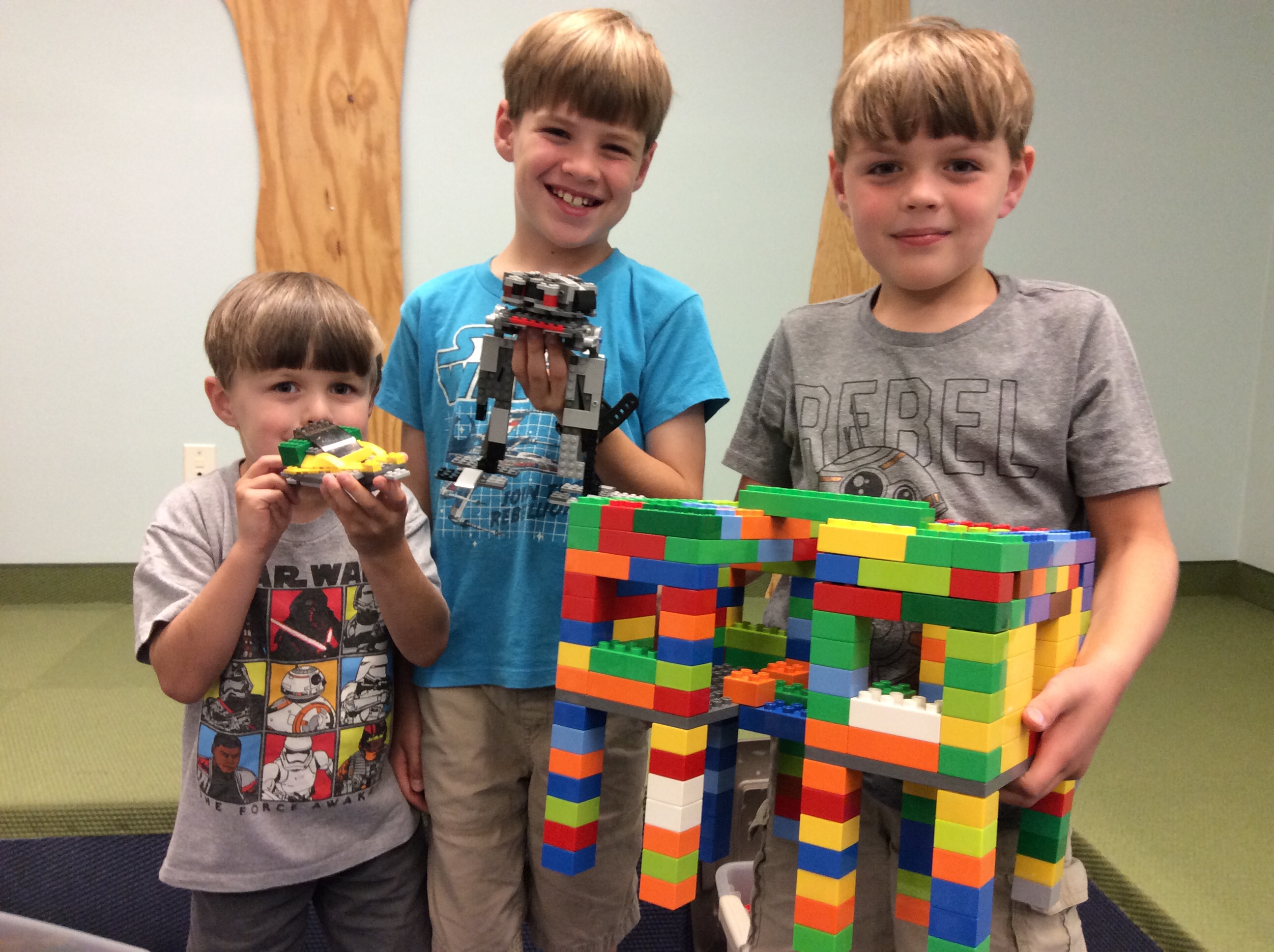 Tres pequeños clientes con sus creaciones de ladrillos LEGO.
