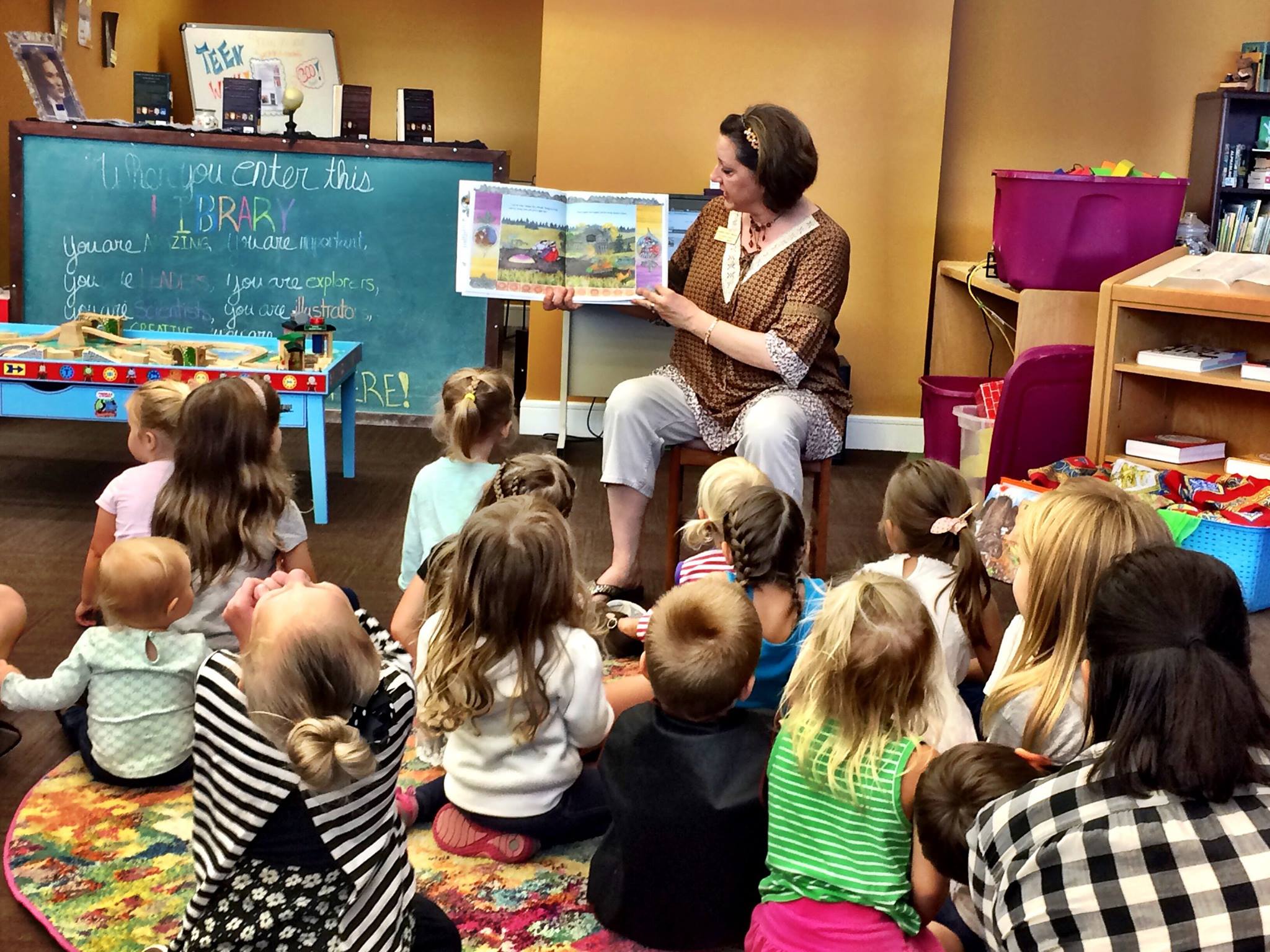 Niños escuchando atentamente a la bibliotecaria de niños leerles una historia.