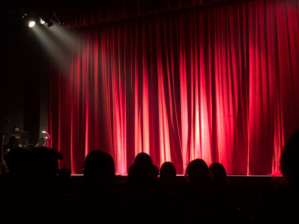 Stage with red curtains and a spotlight.