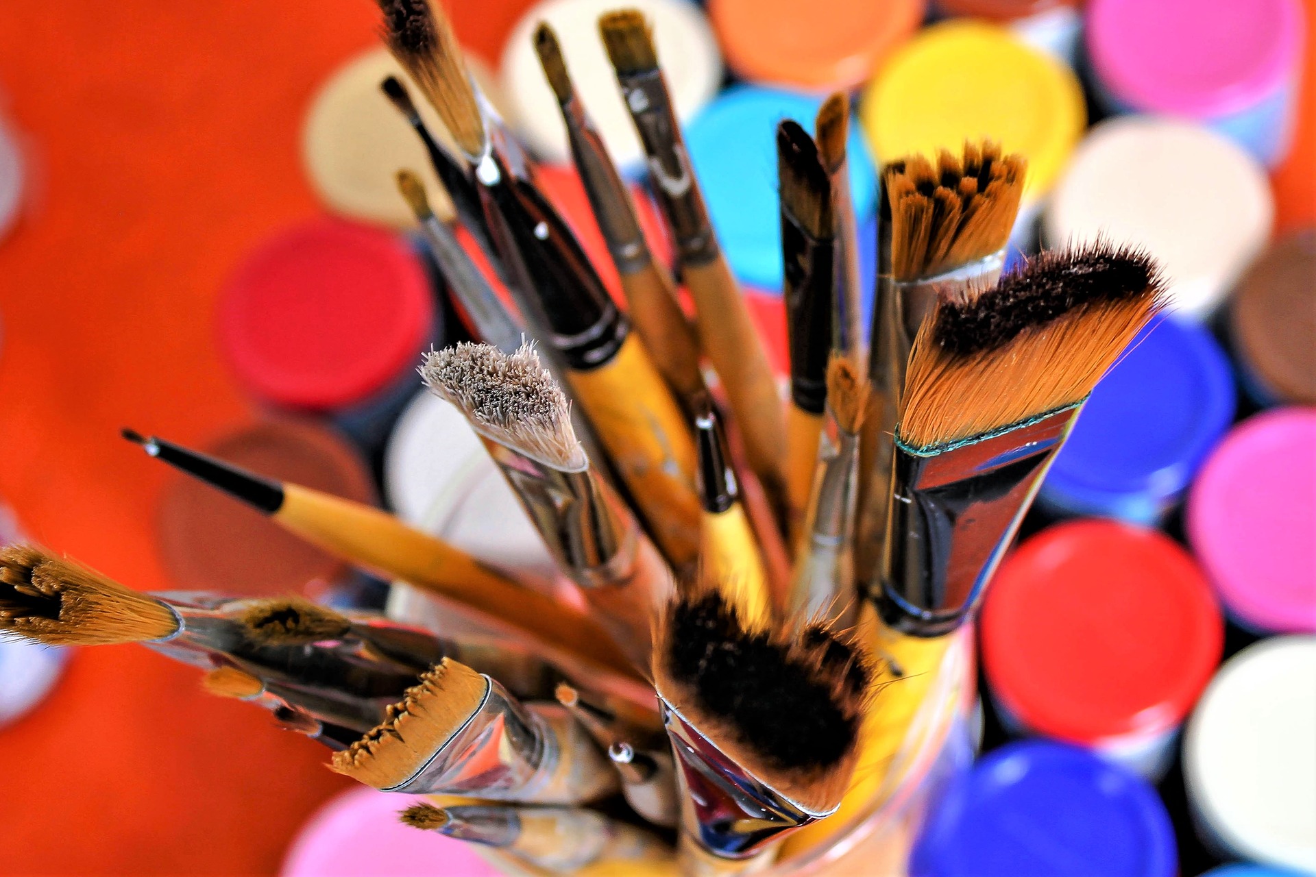 Paintbrushes with colorful paint lids.