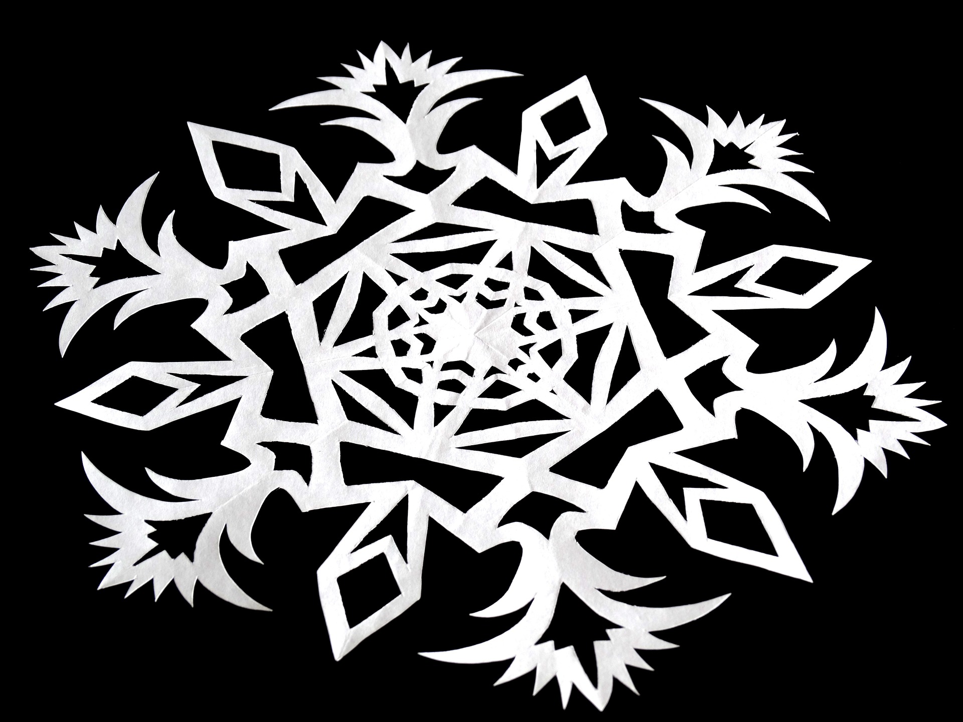 A paper snowflake on a black background.