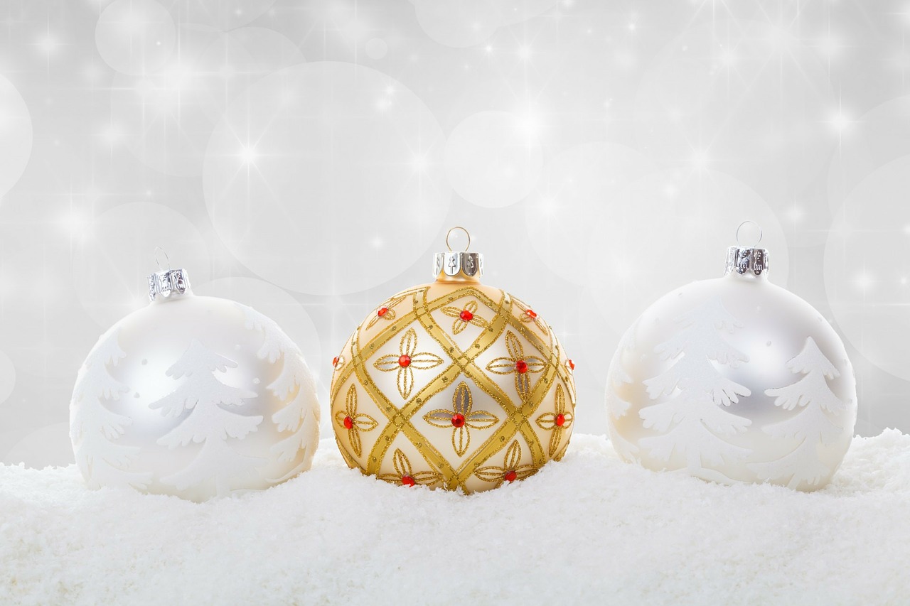 Two christmas ornaments with white trees and one gold one.