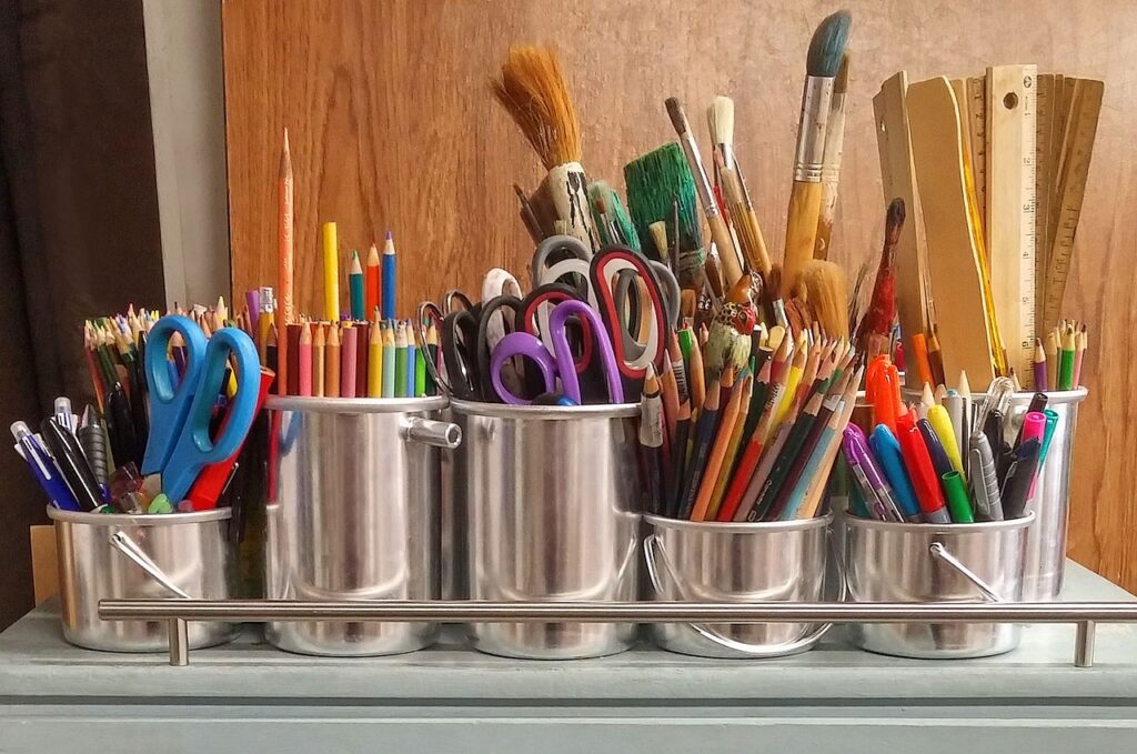 Art supplies in small buckets on a cart.